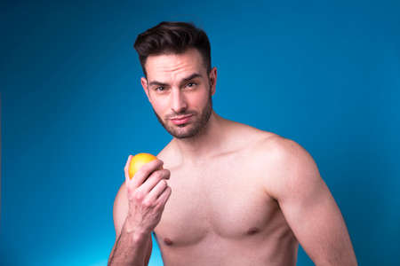 Sexy handsome man holding an orange, inviting and seductive, healthy lifestyle conceptの写真素材