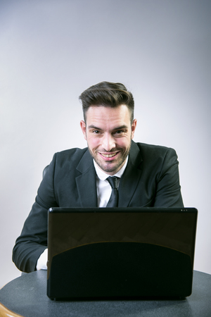 Clever young business man sitting at his desk, working on his laptopの写真素材