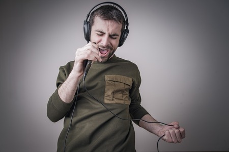 Young man singing karaoke and dancing, moving his body in the rhythm of the musicの写真素材