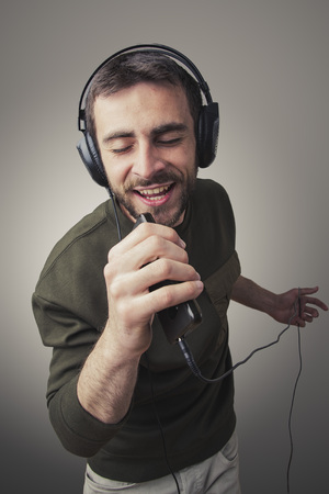 Young man singing karaoke and dancing, moving his body in the rhythm of the musicの写真素材