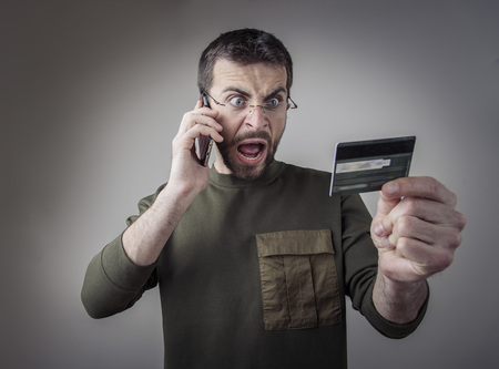 Angry young man having an argument with his bank for the credit card bill he receivedの写真素材