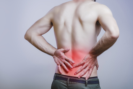 Young caucasian man experiencing lower back painの写真素材
