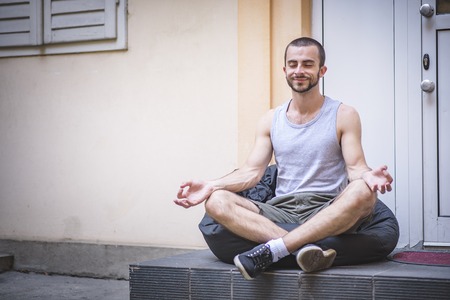 Man doing yoga on a lazy bag outside his homeの写真素材