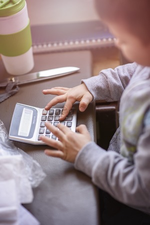 Cute little toddler boy using a calculator, figuring out a math problem, developing logic skillsの写真素材