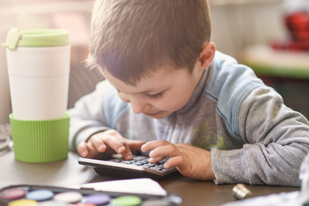 Cute little toddler boy using a calculator, figuring out a math problem, developing logic skillsの写真素材