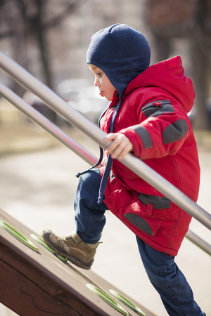 Cute little boy toddler climbing the children fort in the playground, having funの写真素材