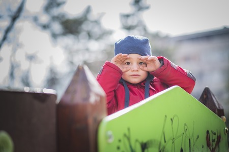 Cute little toddler boy standing on the fort in the playground, pretending hes looking through binoculars, playing pirateの写真素材
