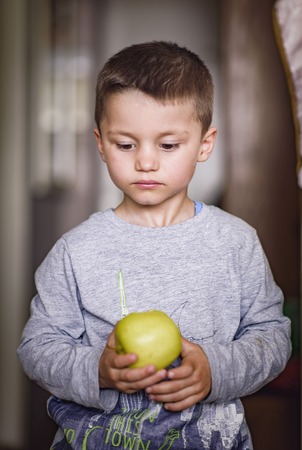 Young caucasian kid, a cute boy, holding an appleの写真素材
