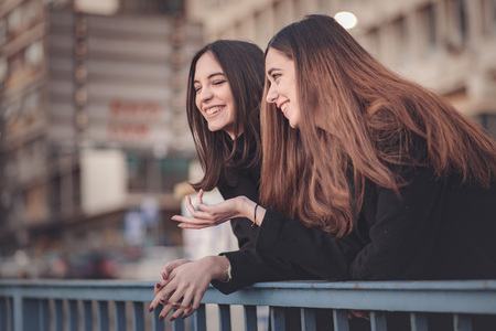 Two beautiful girls on the street having a small chat, enjoying a walkの写真素材