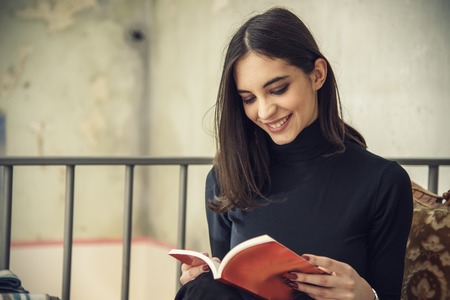 Beautiful girl, a student, reading a book in a coffee shop, enjoying her time aloneの写真素材
