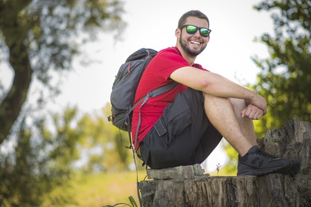 Happy young man with backpack hiking in the woodsの写真素材