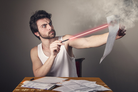 Angry man burning bills and expenses he receives with a laser penの写真素材