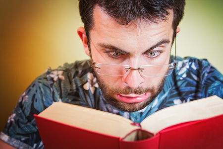 Young man with glasses having troubles reading close and small letters