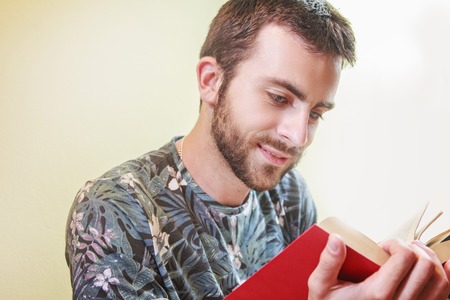 Young man enjoying reading a book very much, immersed in the storyの写真素材