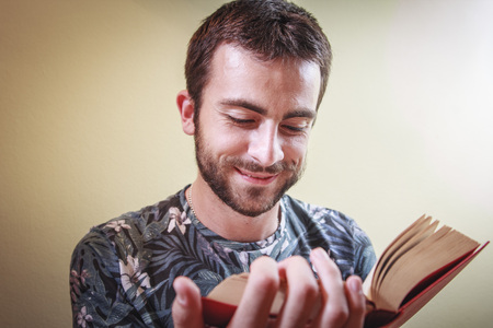Young man enjoying reading a book very much, immersed in the storyの写真素材