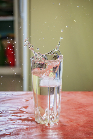 Ice dropping in a glass of water, making a splashの写真素材