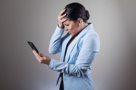Young corporate business woman shocked with a message she receives on her cell phoneの写真素材