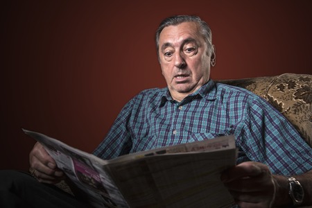 Shocked and outraged senior man with catastrophic news hes reading in the papersの写真素材