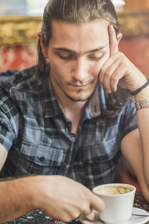 Sad depressed man drinking coffee in a coffee shop, thinking about a break upの写真素材