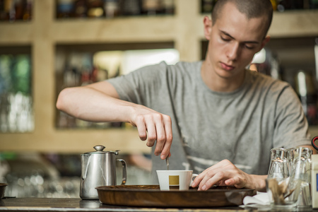 Barista bartender stirring coffee in a small espresso cup in a coffee shopの写真素材
