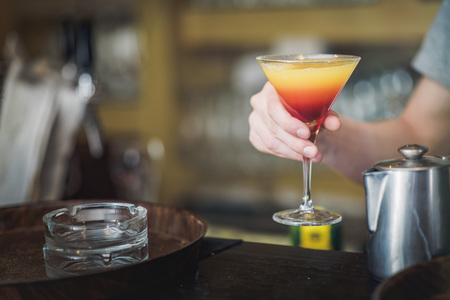 Young bartender making a colorful cocktail, pouring alcohol in a cocktail glassの写真素材
