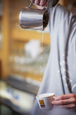 Man pouring milk into espresso cup from above, making a steady streamの写真素材