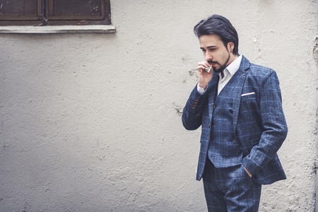 Elegant young business man on a cigarette break, wearing traditional english suit, london style...