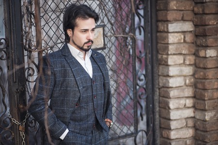 Retro fashioned business man in a typical english suit, tweed coat and waist coat, bearded guy on a street posingの写真素材