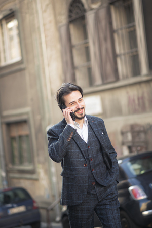 Young fashionable business man having a cheerful phone talkの写真素材