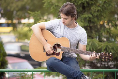 Handsome young man playing guitar outdoors, enjoying his hobbyの写真素材
