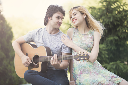 Young cute couple enjoying sunny day, boyfriend playing gutiar for his girlfriendの写真素材