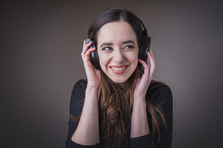 Young woman holding earphones, listening to her favourite music and smilingの写真素材