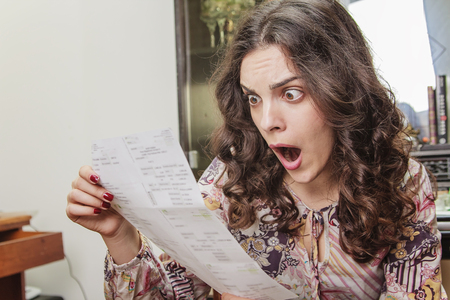 Shocked young woman cant believe the amount of money on her electricity, cable or credit  card billsの写真素材