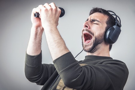 Young man dancing to the sound of the music, singing karaokeの写真素材