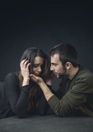 Boyfriend comforting his girlfriend, hugging her and keeping her from harm, woman is crying and feeling sadの写真素材