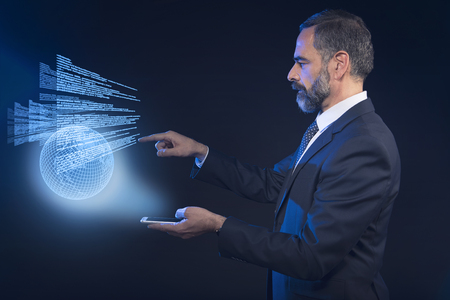 Senior business man scrolling through international news hologram, futuristic concept, or booking a flightの写真素材