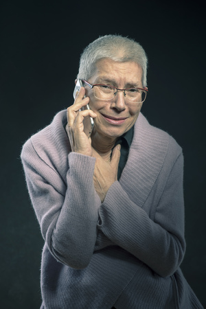 Senior woman receiving painful news of tragedy over her cell phoneの写真素材