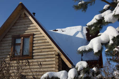 Beautiful winter photo of a wooden house in the snow against the background of the Christmas treeの写真素材