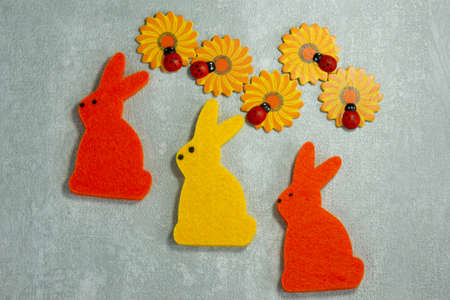 Easter toy bunnies hanging on a clothespin. Handmade orange and yellow hares. Wooden orange flowers...