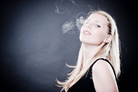 Woman smoking over blackの写真素材