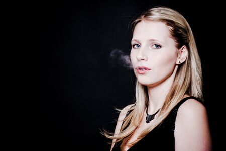 Woman smoking over blackの写真素材