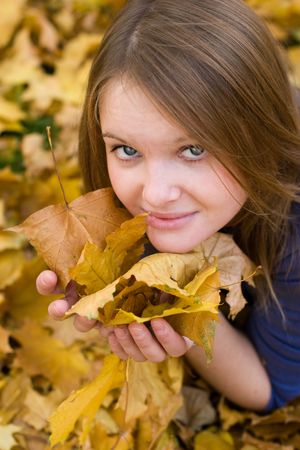 Girl resting in autumn forest, looking at falling leafsの写真素材