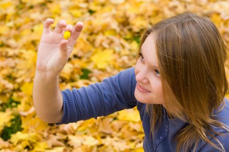 Girl resting in autumn forest, looking at falling leafsの写真素材