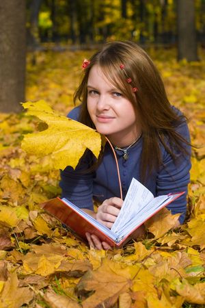 Girl resting in autumn forest, looking at falling leafsの写真素材