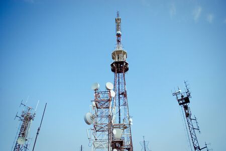Huge communication antenna tower and satellite dishes against blue sky の写真素材
