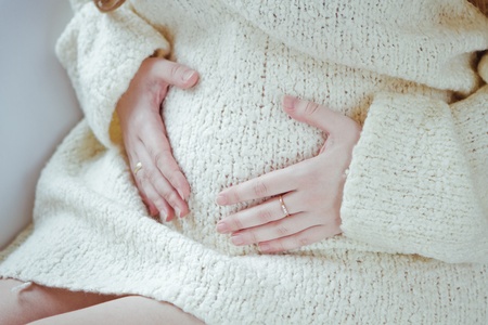 Beautiful young pregnant woman sitting on sofaの写真素材
