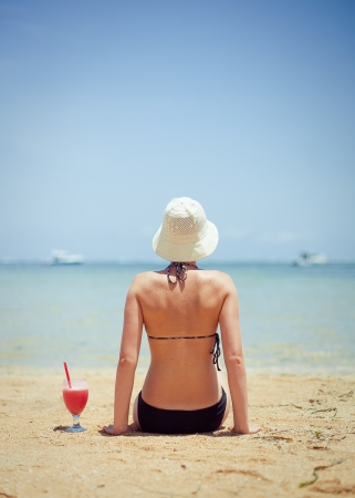 	relaxing woman sitting on sand with cocktail の写真素材