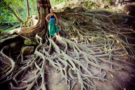 Young woman standing on the tree roots  in Bali islandの写真素材