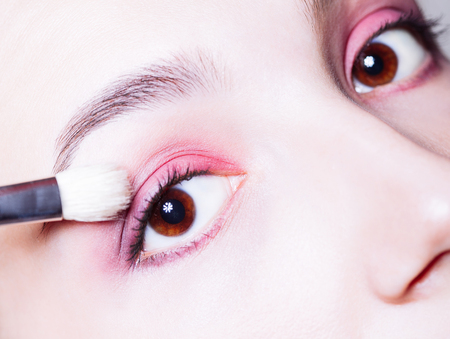 Eye makeup. Woman applying pink eyeshadow powder. Close up shotの写真素材