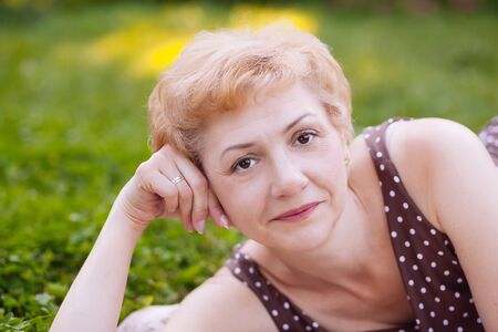 Portrait of middle aged woman smiling on the nature backgroundの写真素材